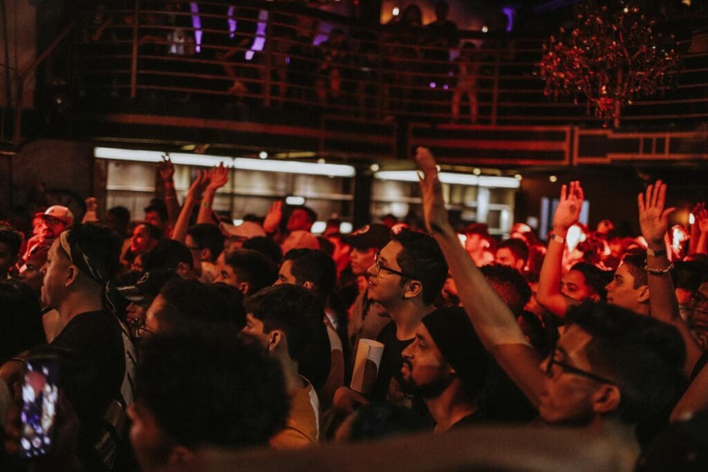Energetic crowd enjoying live music at a vibrant nightclub event with dynamic lighting.