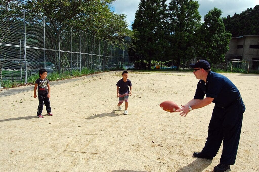 adult playing catch with two children