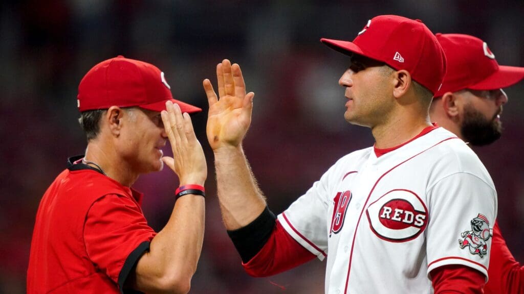 Former Cincinnati Reds first baseman Joey Votto (19) high fives Cincinnati Reds manager David Bell (25) at the conclusion of a baseball game against the Miami Marlins, Thursday, Aug. 19, 2021, at Great American Ball Park in Cincinnati. The Cincinnati Reds won, 6-1.