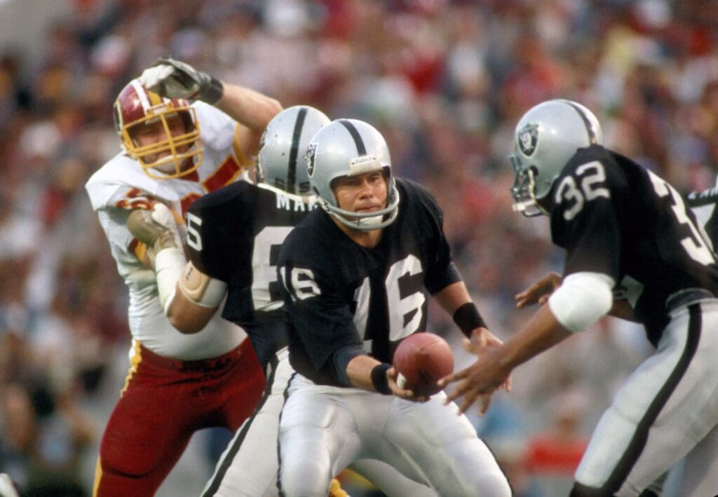 Jan 22, 1984; Tampa, FL, USA; FILE PHOTO; Los Angeles Raiders quarterback Jim Plunkett (16) hands the ball off to Marcus Allen (32) during Super Bowl XVIII against the Washington Redskins at Tampa Stadium. The Raiders defeated the Redskins 38-9. Mandatory Credit: Tony Tomsic-USA TODAY Sports