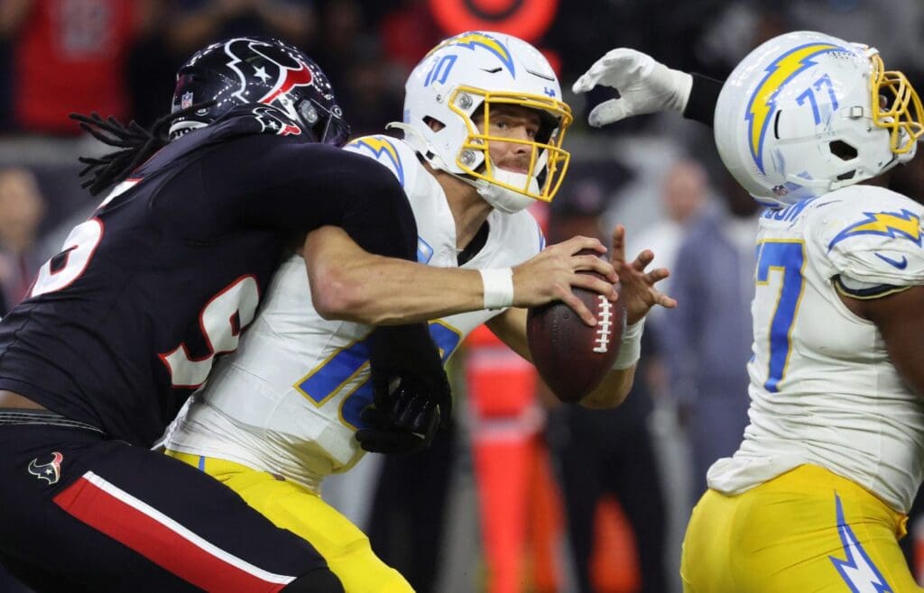 Jan 11, 2025; Houston, Texas, USA; Los Angeles Chargers quarterback Justin Herbert (10) is sacked by Houston Texans defensive end Denico Autry (96) during the third quarter in an AFC wild card game at NRG Stadium.
