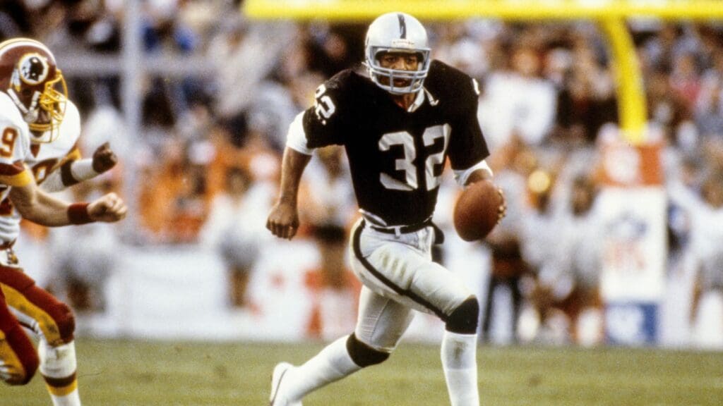 Jan 22, 1984; Tampa, FL, USA; FILE PHOTO; Los Angeles Raiders running back Marcus Allen (32) carries the ball against the Washington Redskins during Super Bowl XVIII at Tampa Stadium. The Raiders defeated the Redskins 38-9 and Allen was named Super Bowl MVP.