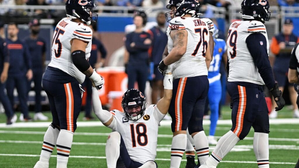 Nov 28, 2024; Detroit, Michigan, USA; Chicago Bears quarterback Caleb Williams (18) gets helped off the turf by offensive tackle Larry Borom (75) and guard Teven Jenkins (76) in the fourth quarter against the Detroit Lions at Ford Field