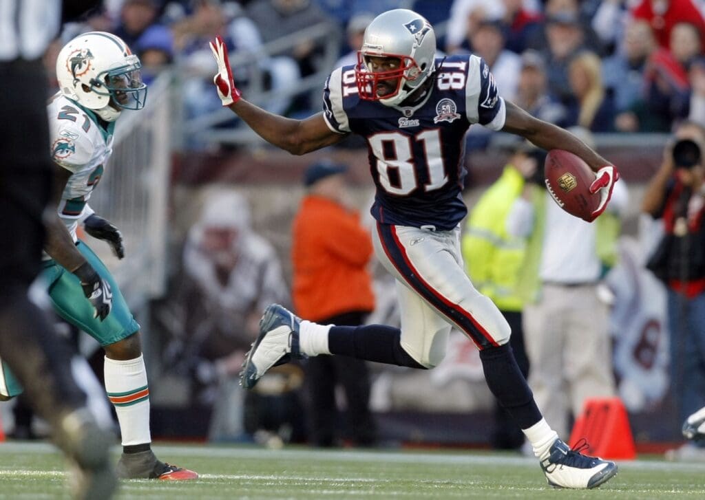 Nov 8, 2009; Foxborough, MA, USA; New England Patriots wide receiver Randy Moss (81) holds off Miami Dolphins cornerback Vontae Davis (21) as he runs for a touchdown during the third quarter at Gillette Stadium. The Patriots defeated Miami 27-17. Mandatory Credit: David Butler II-USA TODAY Sports