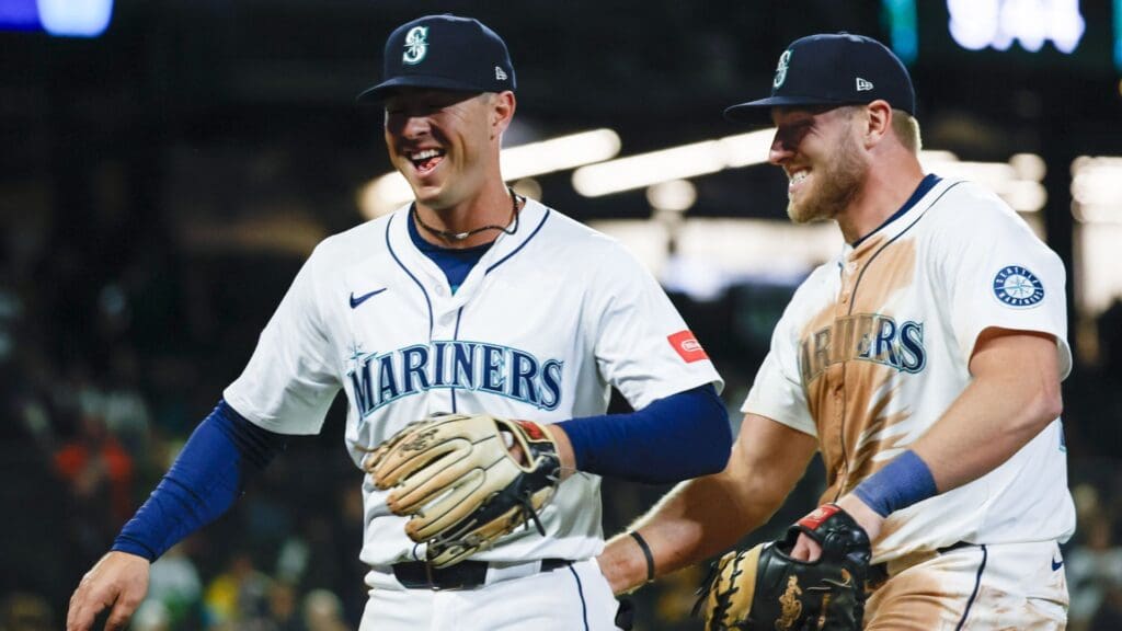 Apr 8, 2025; Seattle, Washington, USA; Seattle Mariners third baseman Dylan Moore (25, left) celebrates with right fielder Luke Raley (20) after turning a double play to end the top of the eleventh inning against the Houston Astros at T-Mobile Park.