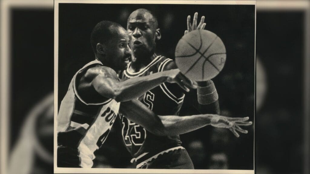 Bucks guard Sidney Moncrief dishes off as Chicago's Michael Jordan nears in 1988. 1988 Press Photo Milwaukee Buck Sidney Moncrief And Chicago S Michael Jordan