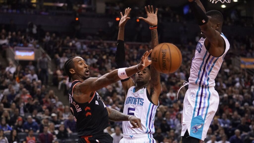Feb 28, 2020; Toronto, Ontario, CAN; Toronto Raptors forward Rondae Hollis-Jefferson (left) passes the ball around Charlotte Hornets guard Nicolas Batum (5) and center Bismack Biyombo (8) at Scotiabank Arena. Charlotte defeated Toronto.