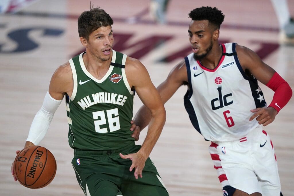 Aug 11, 2020; Lake Buena Vista, Florida, USA; Milwaukee Bucks' Kyle Korver (26) looks to pass while covered by Washington Wizards' Troy Brown Jr. (6) during the first half of an NBA basketball game, Tuesday, Aug. 11, 2020, in Lake Buena Vista, Fla. at Visa Athletic Center