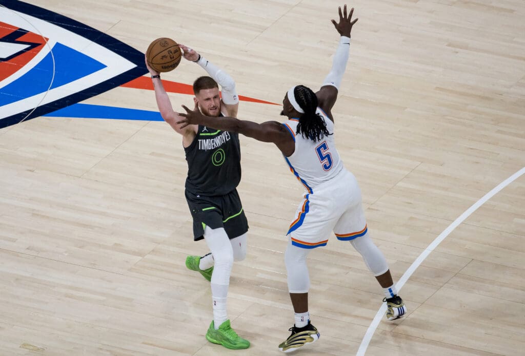 May 20, 2025; Oklahoma City, Oklahoma, USA; Minnesota Timberwolves guard Donte DiVincenzo (0) looks to pass against Oklahoma City Thunder guard Luguentz Dort (5) in the fourth quarter during game one of the western conference finals for the 2025 NBA Playoffs at Paycom Center.