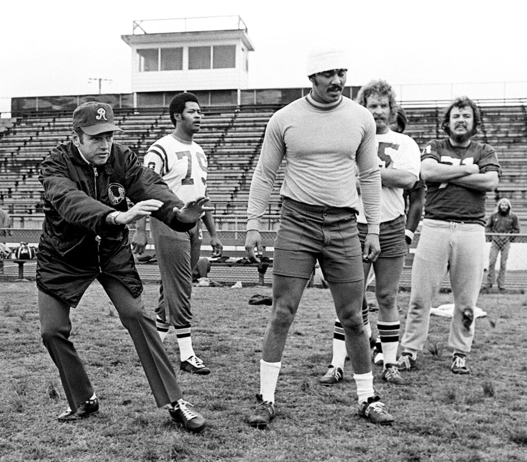 Washington Redskins head coach George Allen, left, directs a few of the 102 aspiring players who appeared at Overton High School to participate in the free agent tryout camp sponsored by the Redskins on March 16, 1974. Coach Allen and seven members of the Redskins staff directed the tryouts.