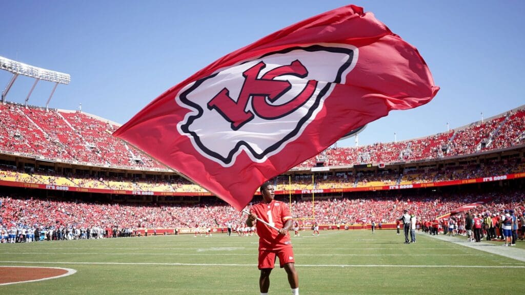 Aug 17, 2024; Kansas City, Missouri, USA; A Kansas City Chiefs staff member waves a large flag against the Detroit Lions after a Chiefs score during the first half at GEHA Field at Arrowhead Stadium