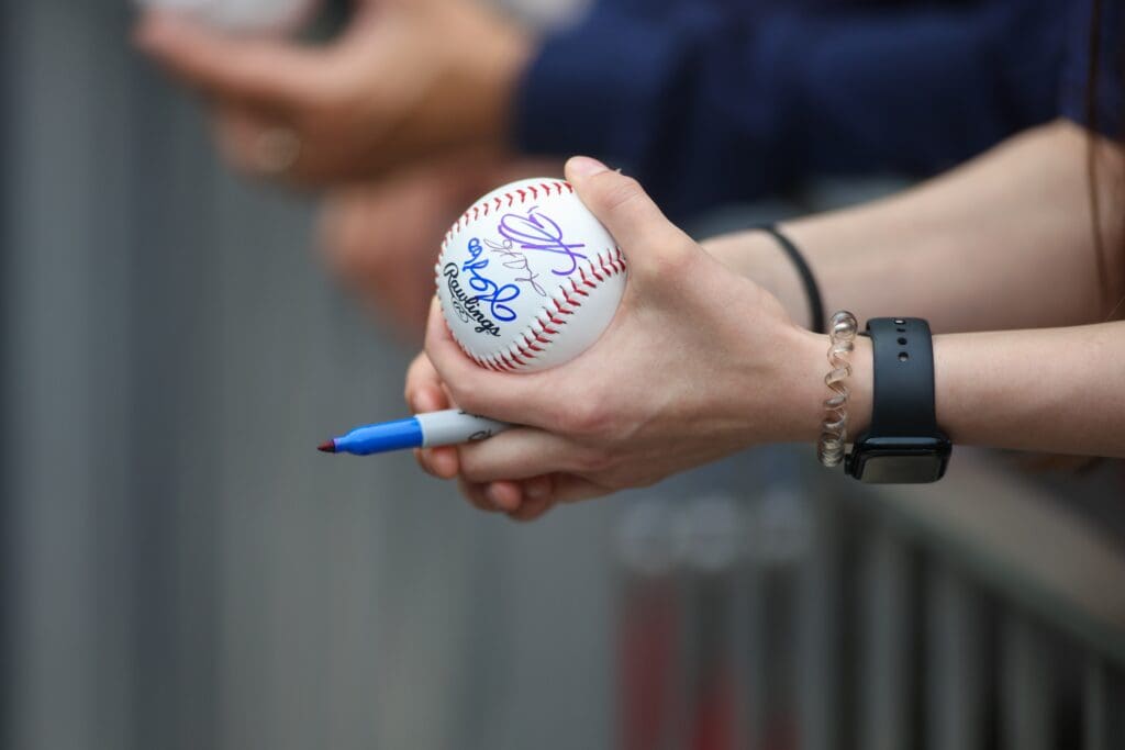 Apr 10, 2024; Atlanta, Georgia, USA; A fan holds a ball signed by Atlanta Braves players during batting practice at Truist Park. The game against the New York Mets was postponed due to impending weather. Mandatory Credit: Brett Davis-Imagn Images Apr 10, 2024; Atlanta, Georgia, USA; New York Mets XXX takes batting practice at Truist Park. The game against the Atlanta Braves was postponed due to impending weather.