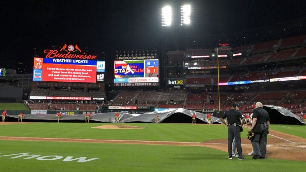 May 19, 2025; St. Louis, Missouri, USA; St. Louis Cardinals grounds crew pulls the tarp on the field as weather moves towards Busch Stadium during the seventh inning between the St. Louis Cardinals and the Detroit Tigers