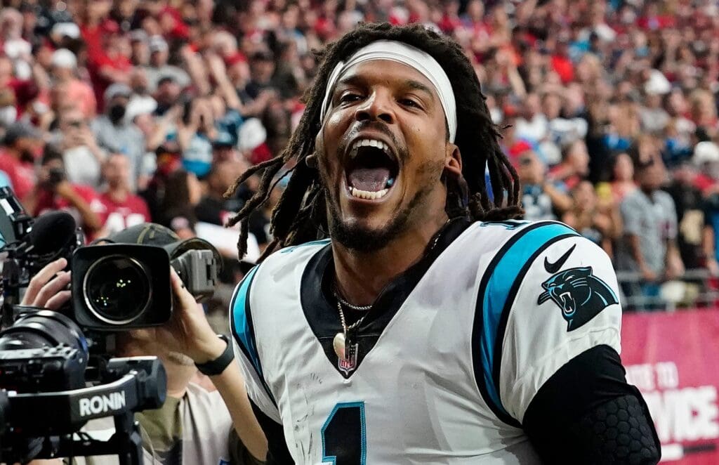 Carolina Panthers quarterback Cam Newton yells \"I'm back!\" after scoring a rushing touchdown against the Arizona Cardinals in a game in 2021.