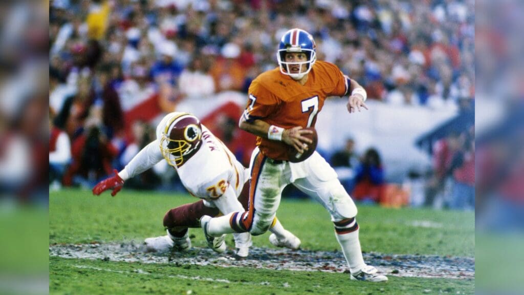 Jan 31, 1988; San Diego, CA, USA; FILE PHOTO; Denver Broncos quarterback John Elway (7) scrambles away from Washington Redskins defensive end Dexter Manley (72) in Super Bowl XXII at the Jack Murphy Stadium. The Redskins defeated the Broncos 42-10 to win their 2nd Super Bowl title.