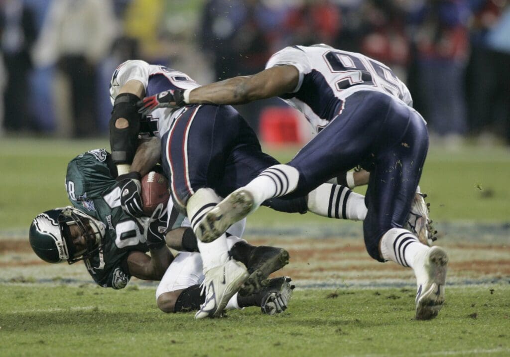 Feb 06, 2005; Jacksonville, FL, USA; Philadelphia Eagles receiver Freddie Mitchell (84) is hit by New England Patriots linebacker Tedy Bruschi (54) and Roman Phifer (95) during Super Bowl XXXIX at Alltel Stadium. The Patriots won the game 24-21.