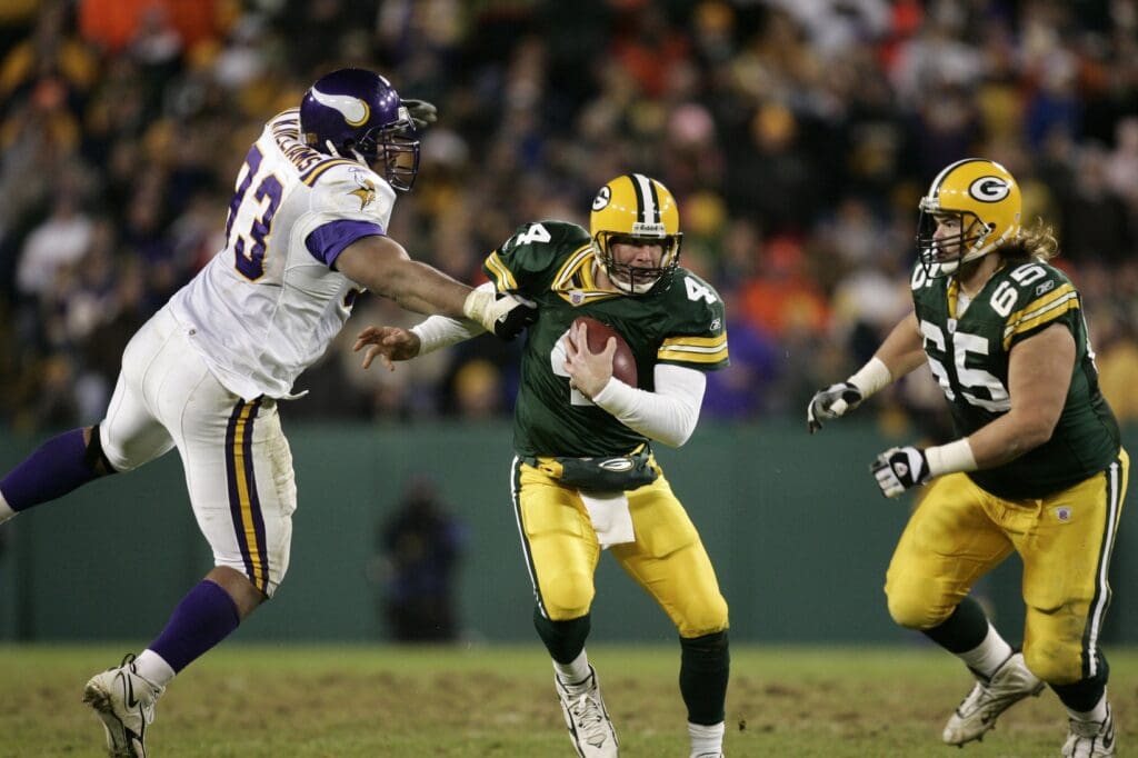November 21, 2005; Green Bay, WI, USA; Green Bay Packers quarterback #4 Brett Favre eludes the grasp of Minnesota Vikings defensive tackle #93 Kevin Williams as Green Bay Packers tackle #65 Mark Tauscher looks on during the third quarter at Lambeau Field.