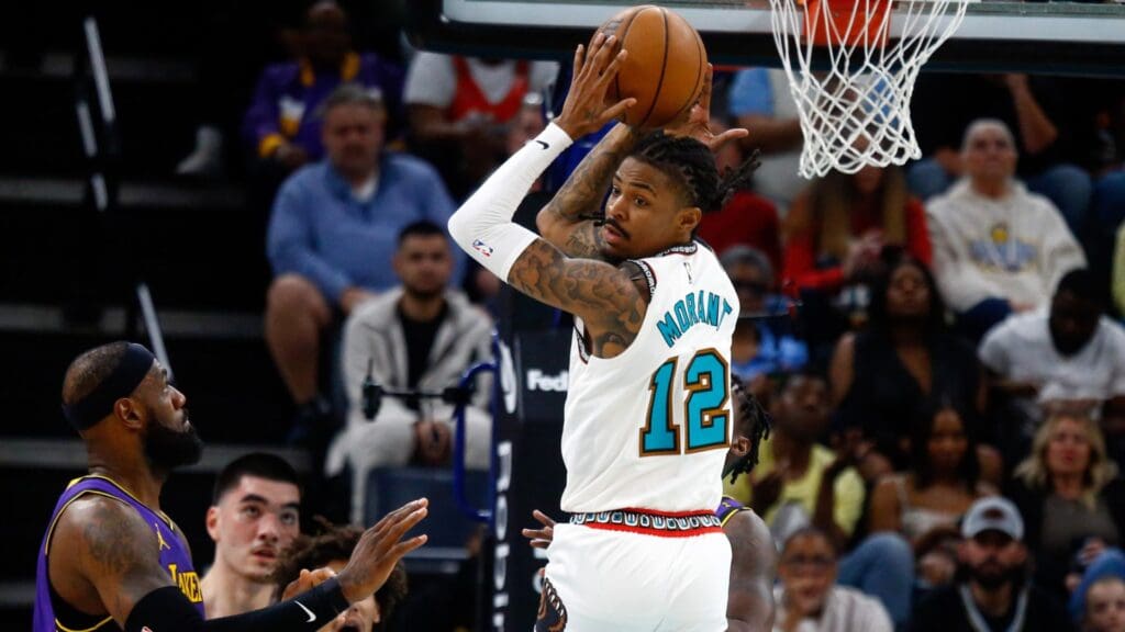 Mar 29, 2025; Memphis, Tennessee, USA; Memphis Grizzlies guard Ja Morant (12) passes the ball as Los Angeles Lakers forward LeBron James (23) defends during the second quarter at FedExForum.