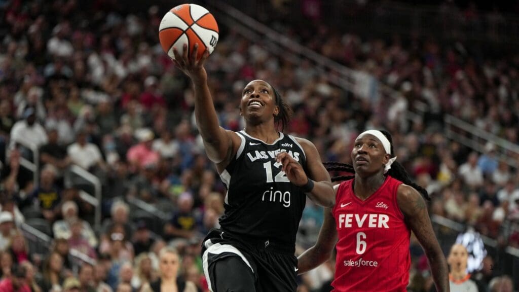 Jun 22, 2025; Las Vegas, Nevada, USA; Las Vegas Aces guard Chelsea Gray (12) scores a layup against Indiana Fever forward Natasha Howard (6) during the first half of a WNBA basketball game at T-Mobile Arena.
