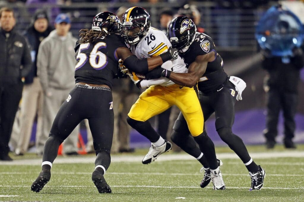 Nov 28, 2013; Baltimore, MD, USA; Pittsburgh Steelers running back LeVeon Bell (26) is tackled by Baltimore Ravens linebacker Josh Bynes (56) and safety James Ihedigbo (32) during a NFL football game on Thanksgiving at M&T Bank Stadium.