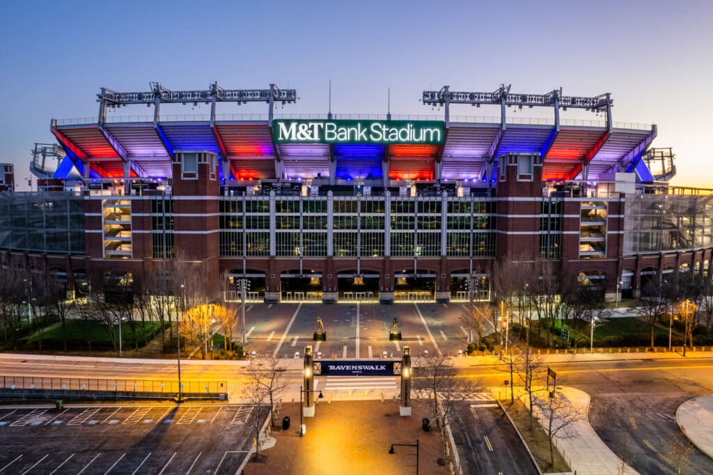 An aerial photograph of M&T Bank Stadium at night lit with red, white, and blue lights for the 2022 Olympics.