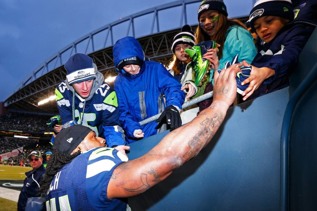 Dec 28, 2014; Seattle, WA, USA; Seattle Seahawks running back Marshawn Lynch (24) gives his shoes and gloves to fans during the final seconds of a 20-6 victory against the St. Louis Rams at CenturyLink Field.