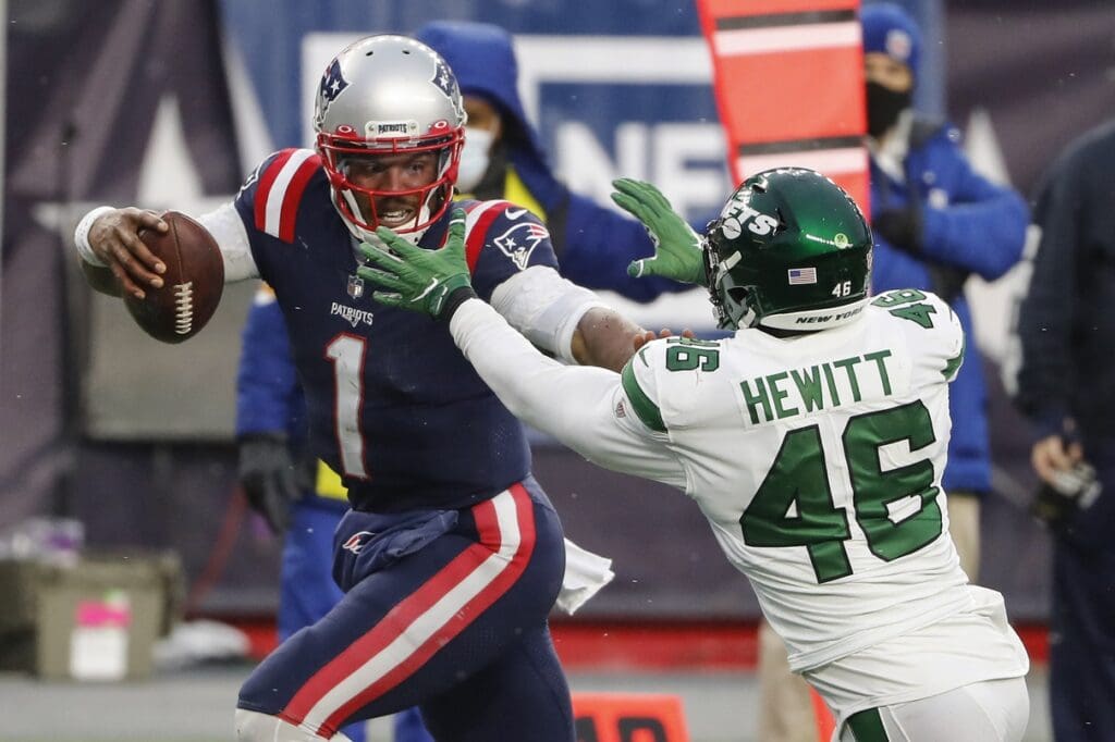 Jan 3, 2021; Foxborough, Massachusetts, USA; New England Patriots quarterback Cam Newton (1) fights off New York Jets linebacker Neville Hewitt (46) on his way to a touchdown during the second half at Gillette Stadium.