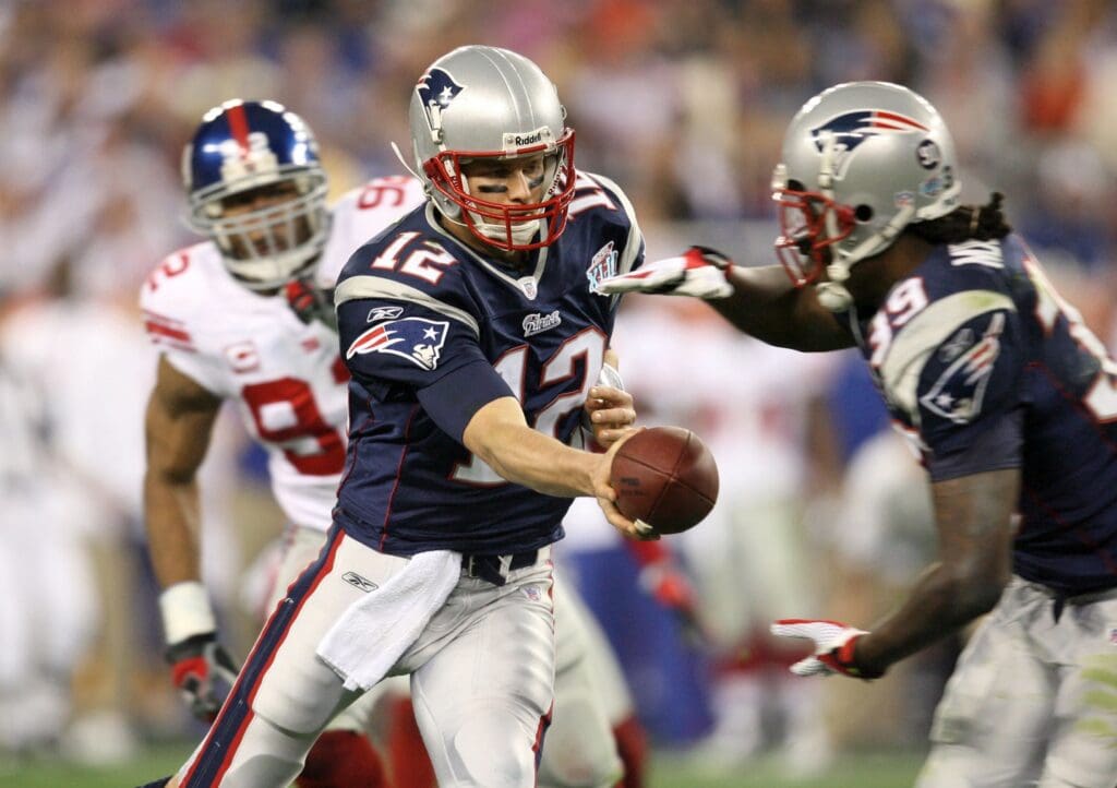 Feb 3, 2008; Glendale, AZ, USA; New England Patriots quarterback Tom Brady (12) hands the ball to running back Laurence Maroney (39) in the first half of Super Bowl XLII against the New York Giants at the University of Phoenix Stadium.