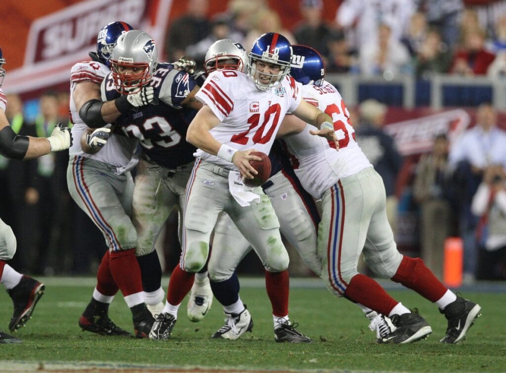 Feb 3, 2008; Glendale, AZ, USA; New York Giants quarterback Eli Manning (10) scrambles out of the grasp of New England defensive lineman Richard Seymour (93) in the fourth quarter of Super Bowl XLII at the University of Phoenix Stadium. New York Giants defeated the New England Patriots with a final of 17-14.