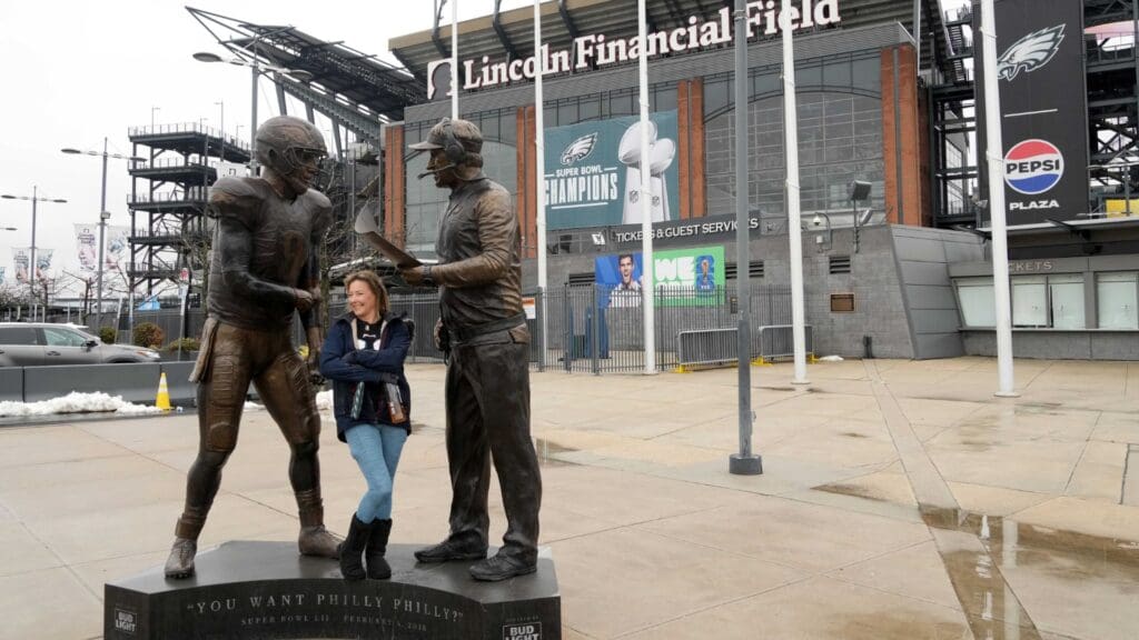 Feb 13, 2025; Philadelphia, PA, USA; A fan poses with the Super Bowl 57 Philly Special statue featuring Philadelphia Eagles quarterback Nick Foles and coach Doug Pederson at Lincoln Financial Field.