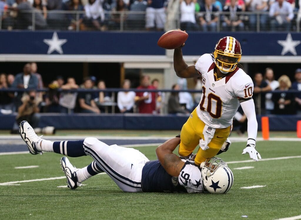Nov 22, 2012; Arlington, TX, USA; Washington Redskins quarterback Robert Griffin III (10) throws throws the ball away to avoid the sack from Dallas Cowboys defensive tackle Jason Hatcher (97) during a game on Thanksgiving at Cowboys Stadium.