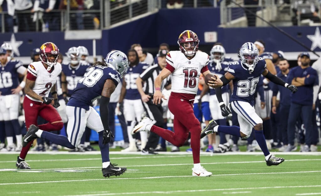 Jan 5, 2025; Arlington, Texas, USA; Washington Commanders quarterback Marcus Mariota (18) run past Dallas Cowboys safety Malik Hooker (28) during the fourth quarter at AT&T Stadium. Mandatory Credit: Kevin Jairaj-Imagn Images