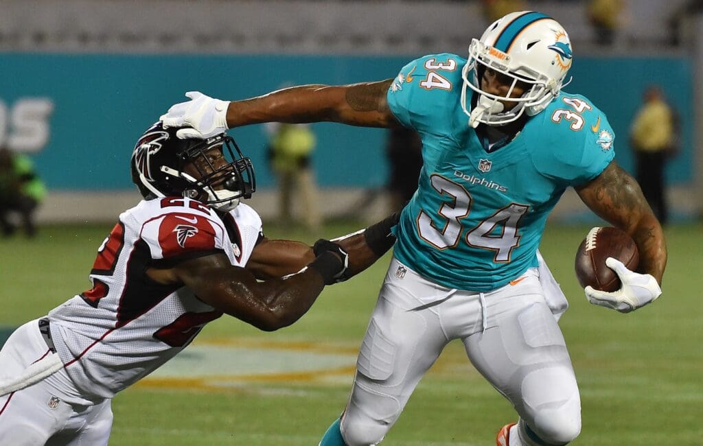 Aug 25, 2016; Orlando, FL, USA; Miami Dolphins running back Arian Foster (34) avoids the tackle of Atlanta Falcons strong safety Keanu Neal (22) during the first half at Camping World Stadium.