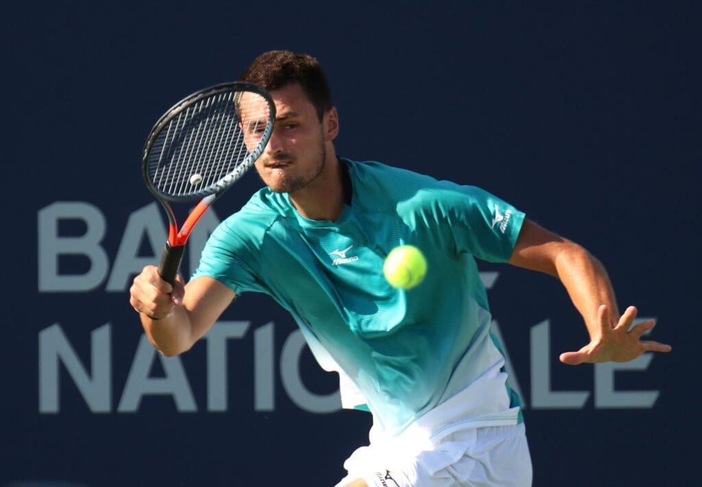 Aug 5, 2019; Montreal, Quebec, Canada; Bernard Tomic from Australia hits a shot against Roberto Bautista Agut from Spain (not pictured) during the Rogers Cup tennis tournament at Stade IGA.