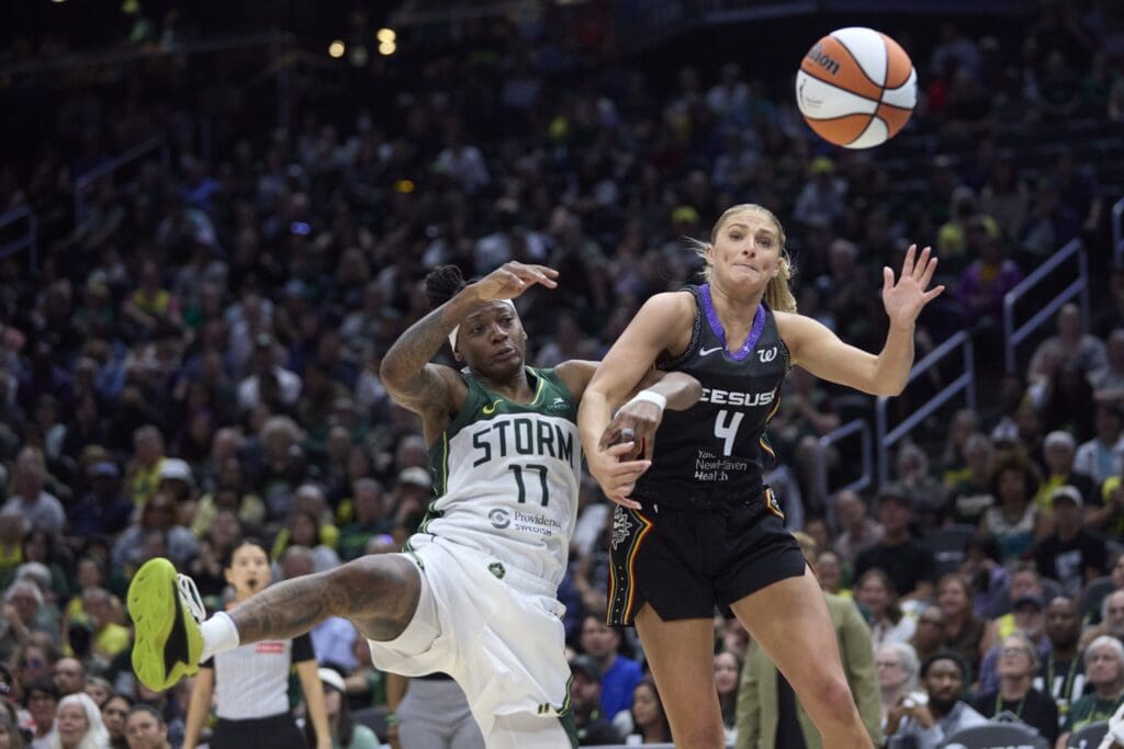 Jul 11, 2025; Seattle, Washington, USA; Connecticut Sun guard Jacy Sheldon (4) and Seattle Storm guard Erica Wheeler (17) battle for a rebound during the second half at Climate Pledge Arena.