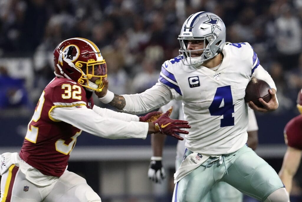 Dec 29, 2019; Arlington, Texas, USA; Dallas Cowboys quarterback Dak Prescott (4) stiff arms Washington Redskins cornerback Jimmy Moreland (32) during the second half at AT&T Stadium.
