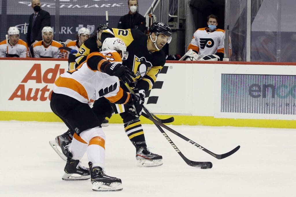 Mar 6, 2021; Pittsburgh, Pennsylvania, USA; Pittsburgh Penguins center Zach Aston-Reese (12) shoots the puck as Philadelphia Flyers right wing Travis Konecny (11) defends during the third period at PPG Paints Arena. The Penguins won 4-3. 