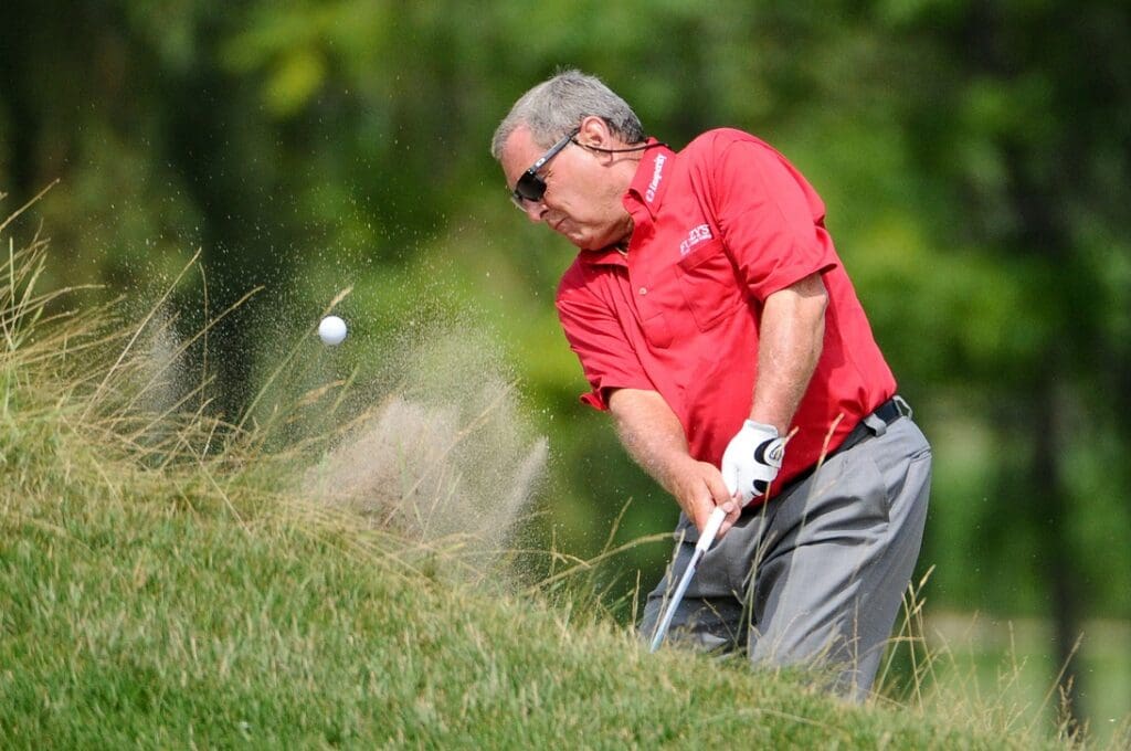 July 14, 2012; Lake Orion, MI, USA; Fuzzy Zoeller (USA) hits out of a bunker on the 13th green during the third round of the U.S. Senior Open at Indianwood Golf and Country Club.