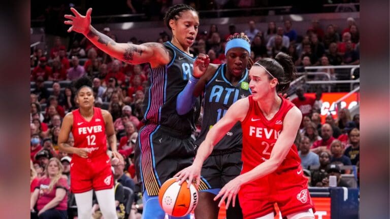 Indiana Fever guard Caitlin Clark (22) passes around Atlanta Dream guard Rhyne Howard (10) and center Brittney Griner (42).