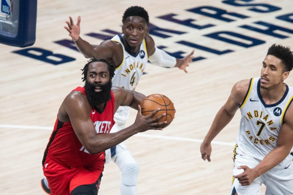 Jan 6, 2021; Indianapolis, Indiana, USA; Houston Rockets guard James Harden (13) dribbles the ball between Indiana Pacers guard Victor Oladipo (4) and guard Malcolm Brogdon (7) in the fourth quarter at Bankers Life Fieldhouse. 