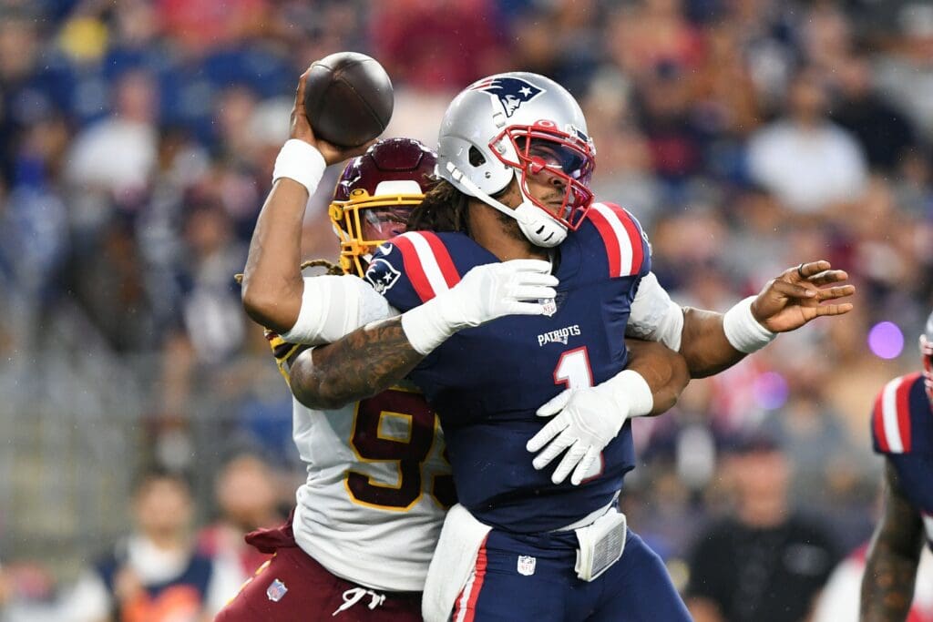 Aug 12, 2021; Foxborough, Massachusetts, USA; New England Patriots quarterback Cam Newton (1) throws the ball under pressure from Washington Football Team defensive end Chase Young (99) during the first half at Gillette Stadium.