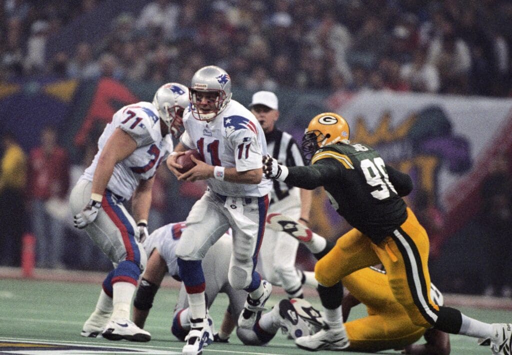 Jan 26, 1997; New Orleans, LA, USA; FILE PHOTO; New England Patriots quarterback Drew Bledsoe (11) is chased by Green Bay Packers defensive end Sean Jones (96) during Super Bowl XXXI at the Superdome. The Packers defeated the Patriots 35-21. 