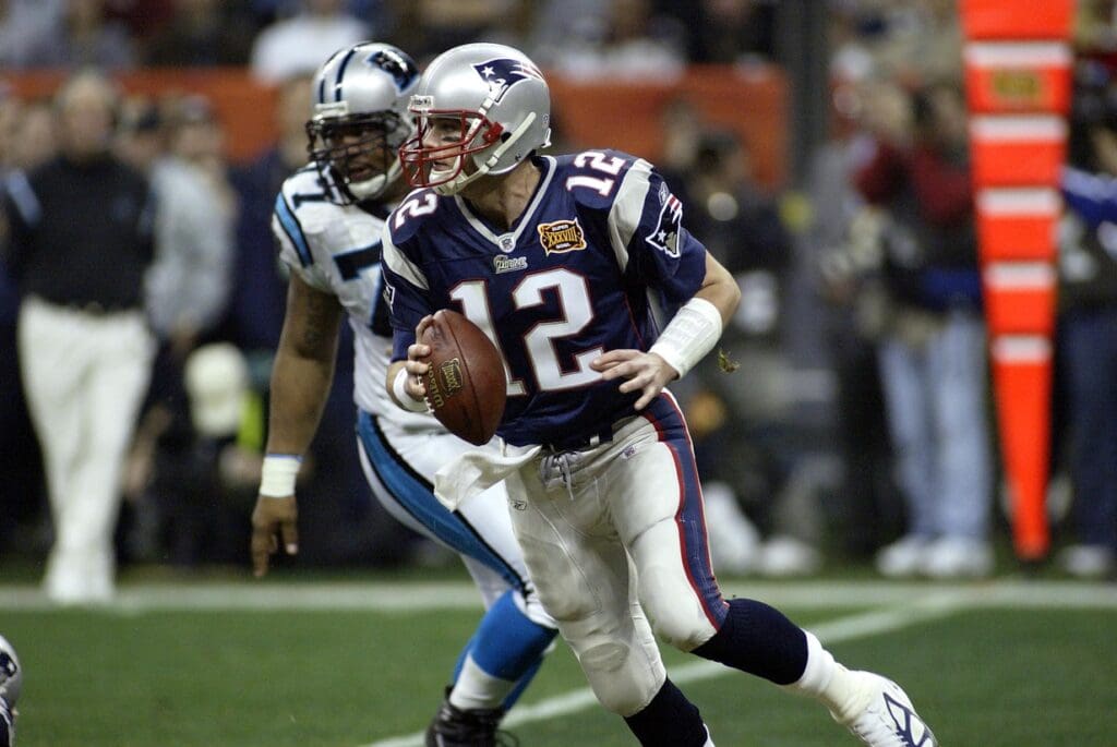 Feb 1, 2004; Houston, TX, USA; FILE PHOTO; New England Patriots quarterback Tom Brady is chased by Carolina Panthers defensive tackle Kris Jenkins (77) during Super Bowl XXXVIII at Reliant Stadium. The Patriots defeated the Panthers 32-29.