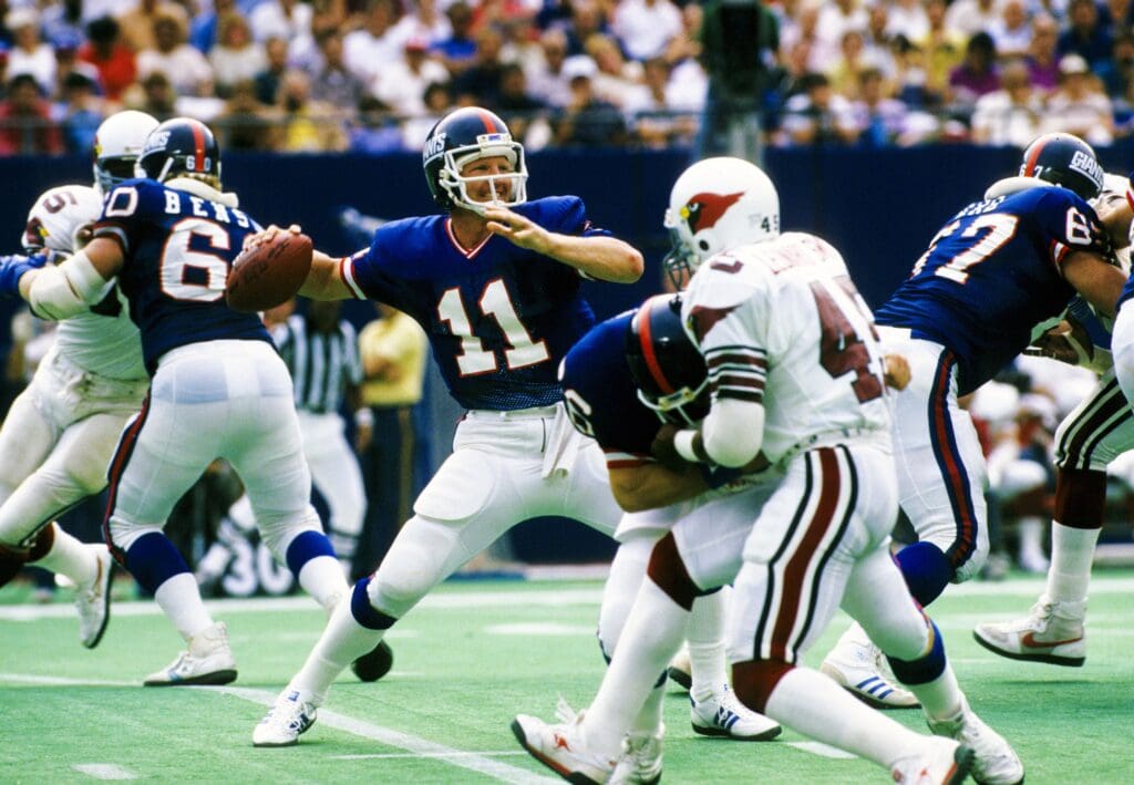 Sep 22, 1985; East Rutherford, NJ, USA; FILE PHOTO; New York Giants quarterback Phil Simms (11) throws the ball under pressure from St. Louis Cardinals safety Leonard Smith (45) at Giants Stadium during the 1985 season.
