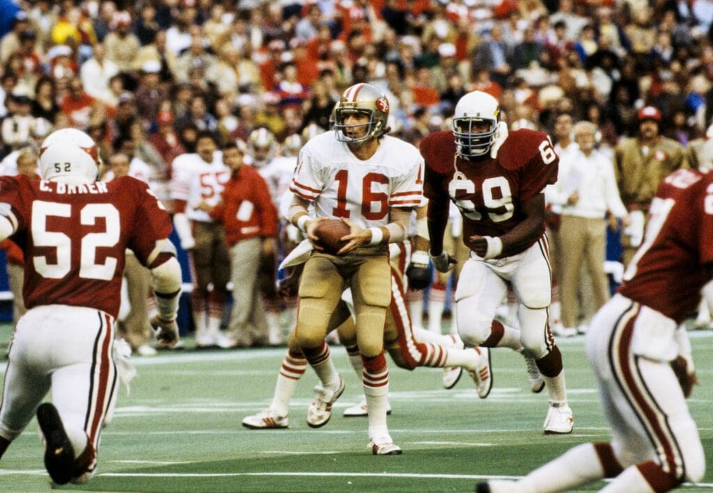 Nov 19, 1982; St. Louis, MO, USA; FILE PHOTO; San Francisco 49ers quarterback Joe Montana (16) carries the ball against the St. Louis Cardinals while Cardinals defensive tackle Rush Brown (69) looks to sack at Busch Stadium. The 49ers defeated the Cardinals 31-2.