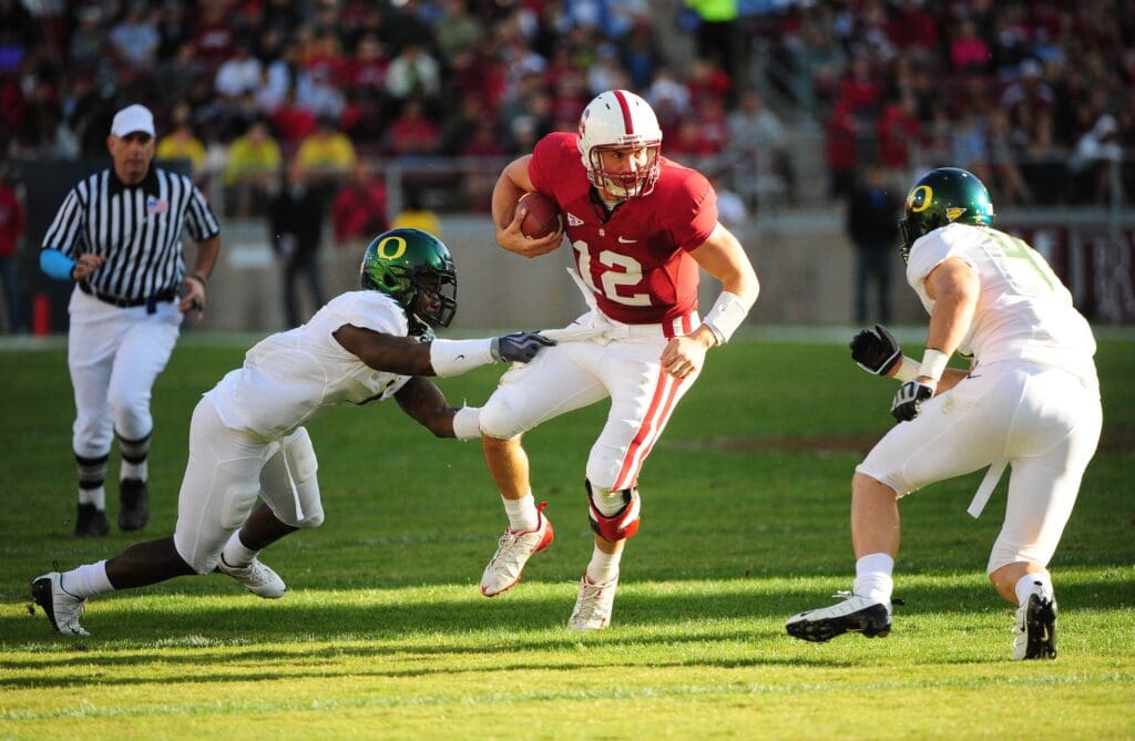 November 7, 2009; Stanford, CA, USA; Stanford Cardinal quarterback Andrew Luck (12) runs between two Oregon Ducks defenders during the fourth quarter at Stanford Stadium. The Cardinal defeated the Ducks 51-42. 