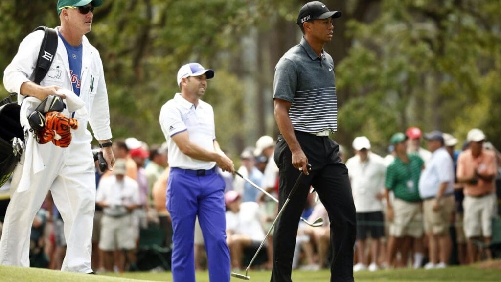 Apr 11, 2015; Augusta, GA, USA; Tiger Woods (right) and caddie Joe LaCava (left) walk past Sergio Garcia (middle) on the 1st fairway during the third round of The Masters golf tournament at Augusta National Golf Club.