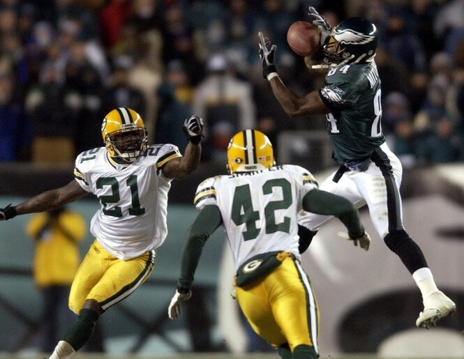 Philadelphia Eagles receiver Freddie Mitchell snares a pass for first down when it was fourth and 26 while being covered by Green Bay Packers Bhawoh Jue (21) and Darren Sharper late in the fourth quarter of their game Sunday, January 11, 2004 at Lincoln Financial Field in Philadelphia.