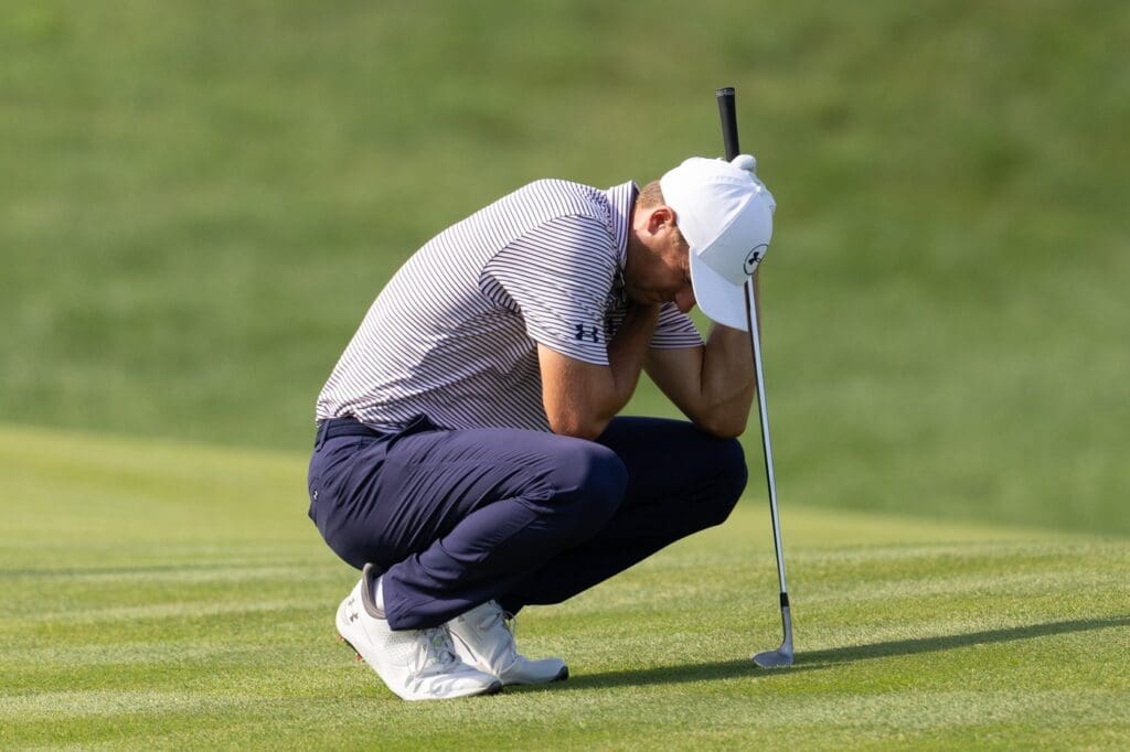 Jun 19, 2025; Cromwell, Connecticut, USA; Jordan Spieth crouches while grabbing his upper body on the 12th hole during the first round of the Travelers Championship golf tournament. Mandatory Credit: Bill Streicher-Imagn Images