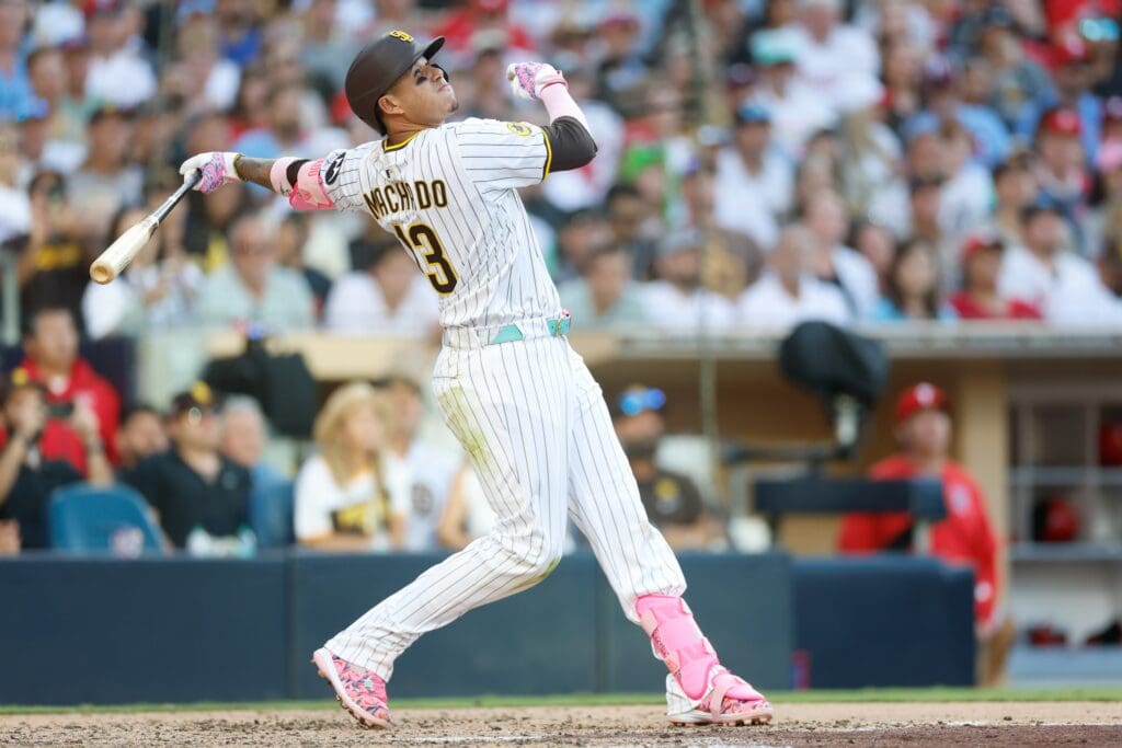 Jul 12, 2025; San Diego, California, USA; San Diego Padres third baseman Manny Machado (13) hits a sacrifice fly during the seventh inning against the Philadelphia Phillies at Petco Park. Mandatory Credit: David Frerker-Imagn Images